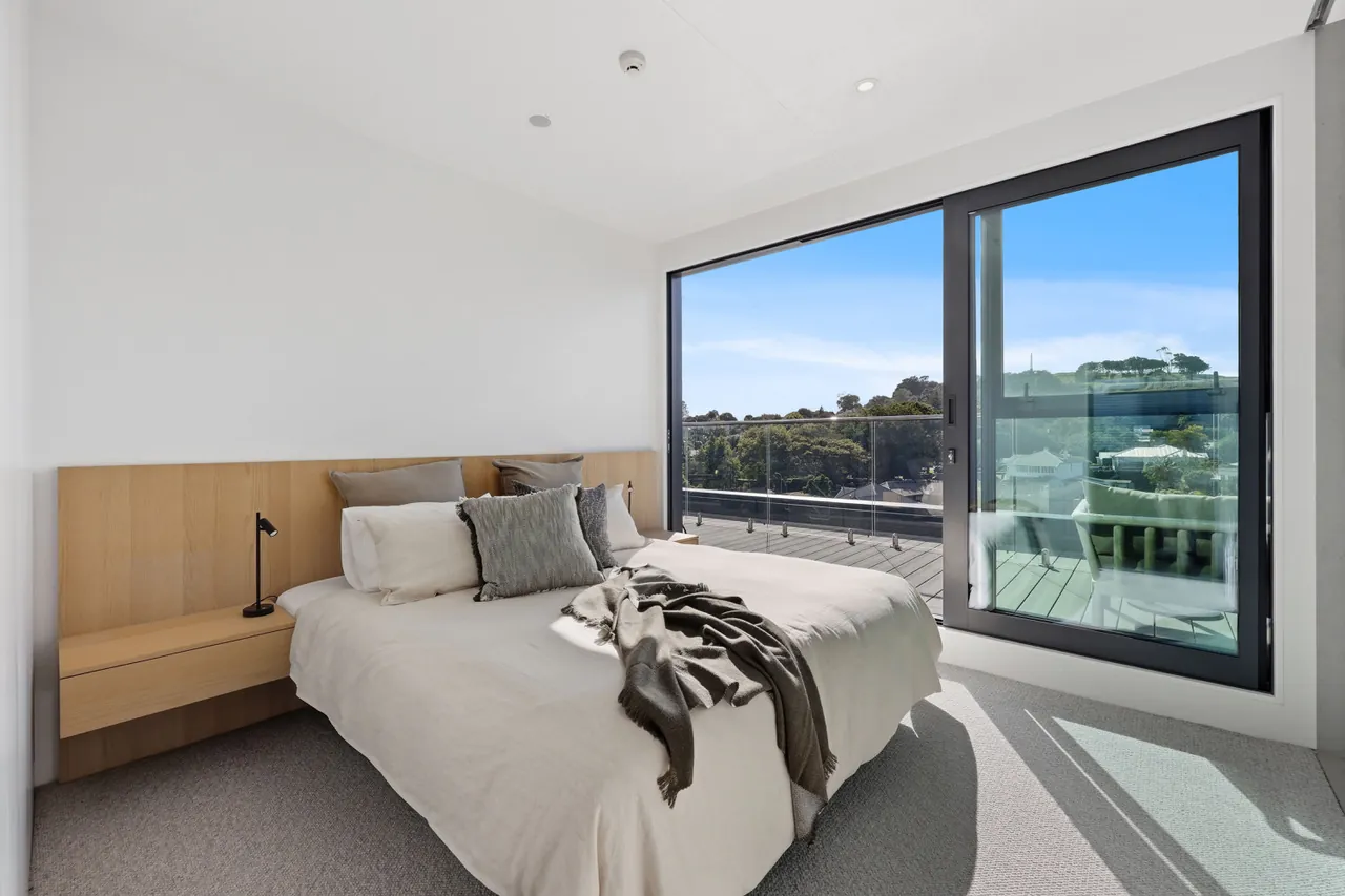 The master bedroom at Penthouse 505, oak headboard and sliding doors opening onto the terrace
