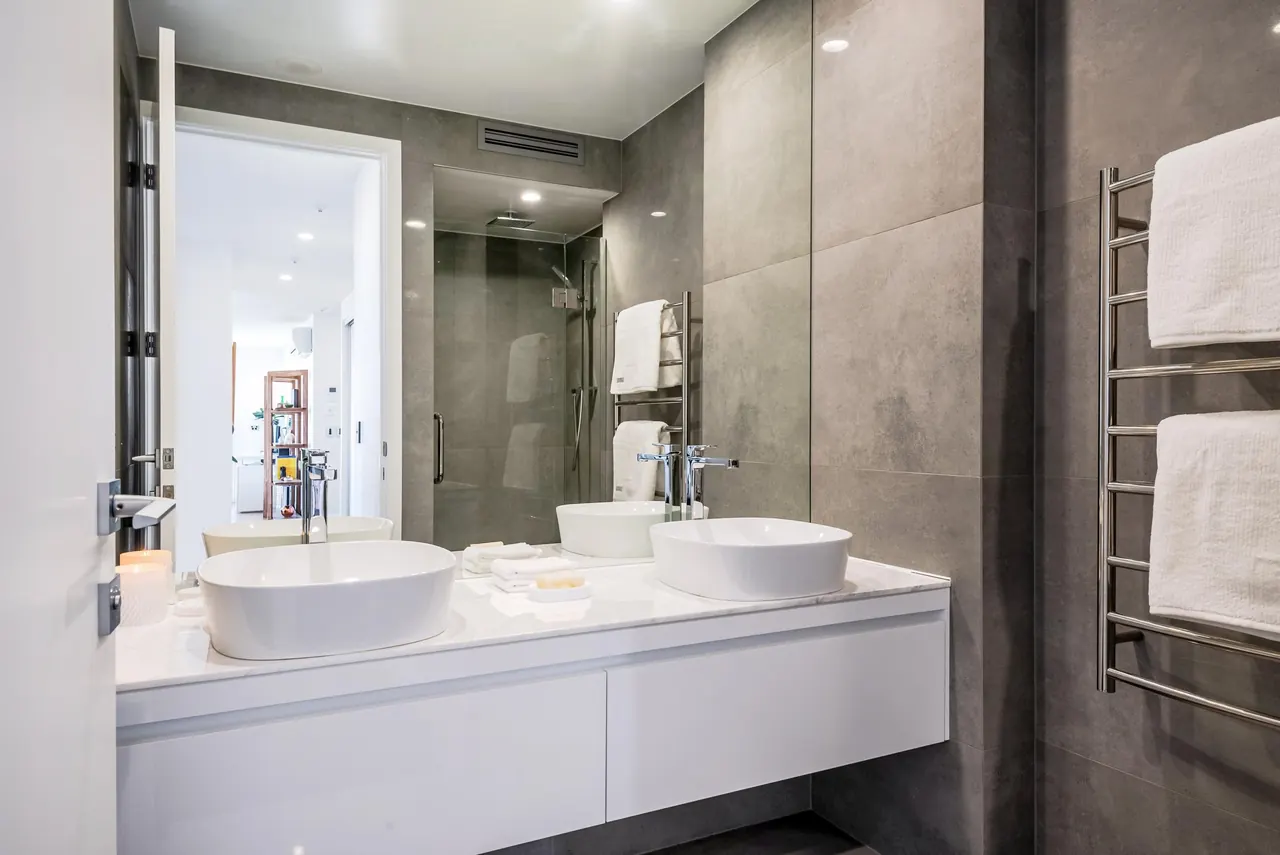A bathroom with double basins and a heated towel rail