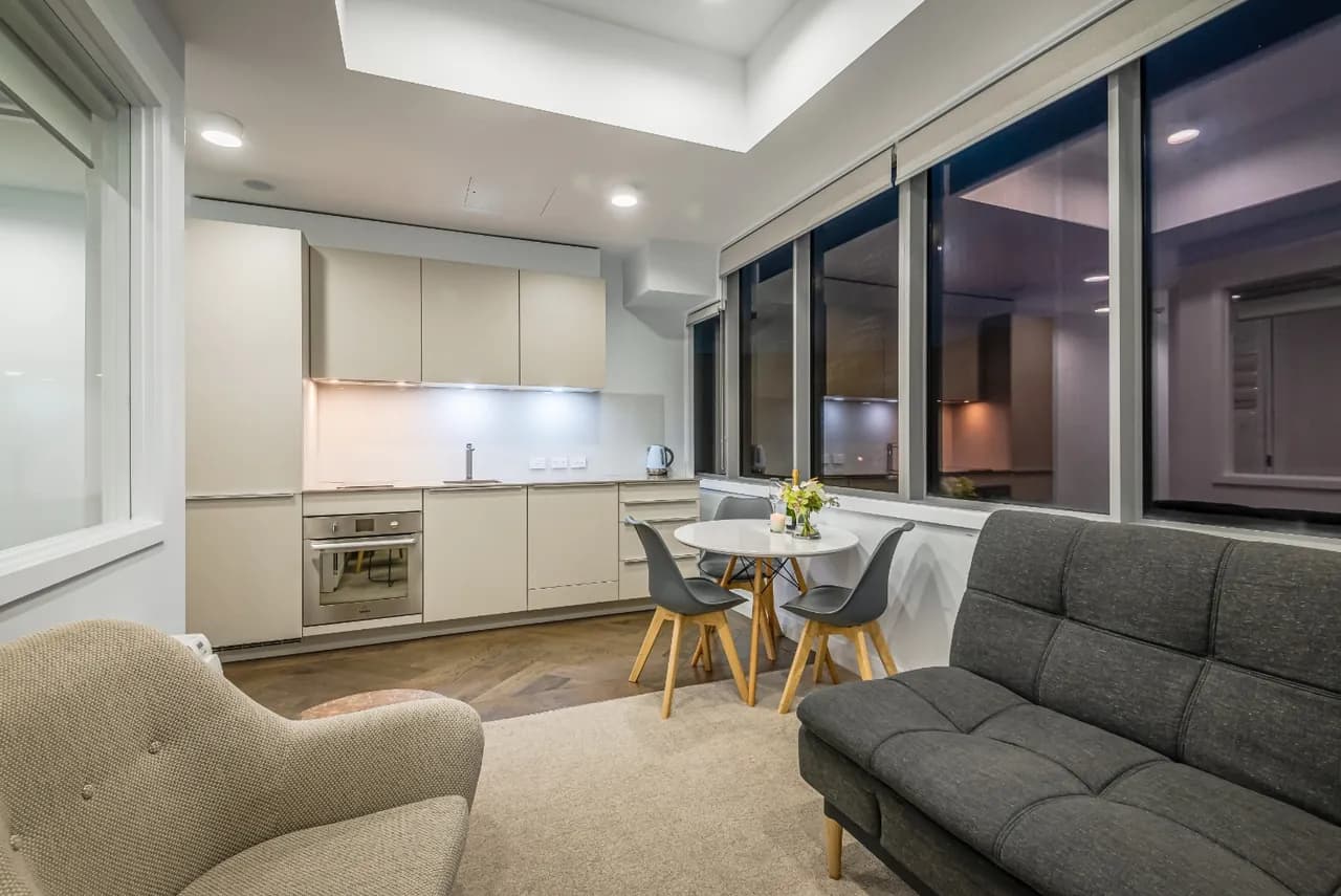 A guest apartment at Western Park at dusk, with its kitchen, dining table and lounge